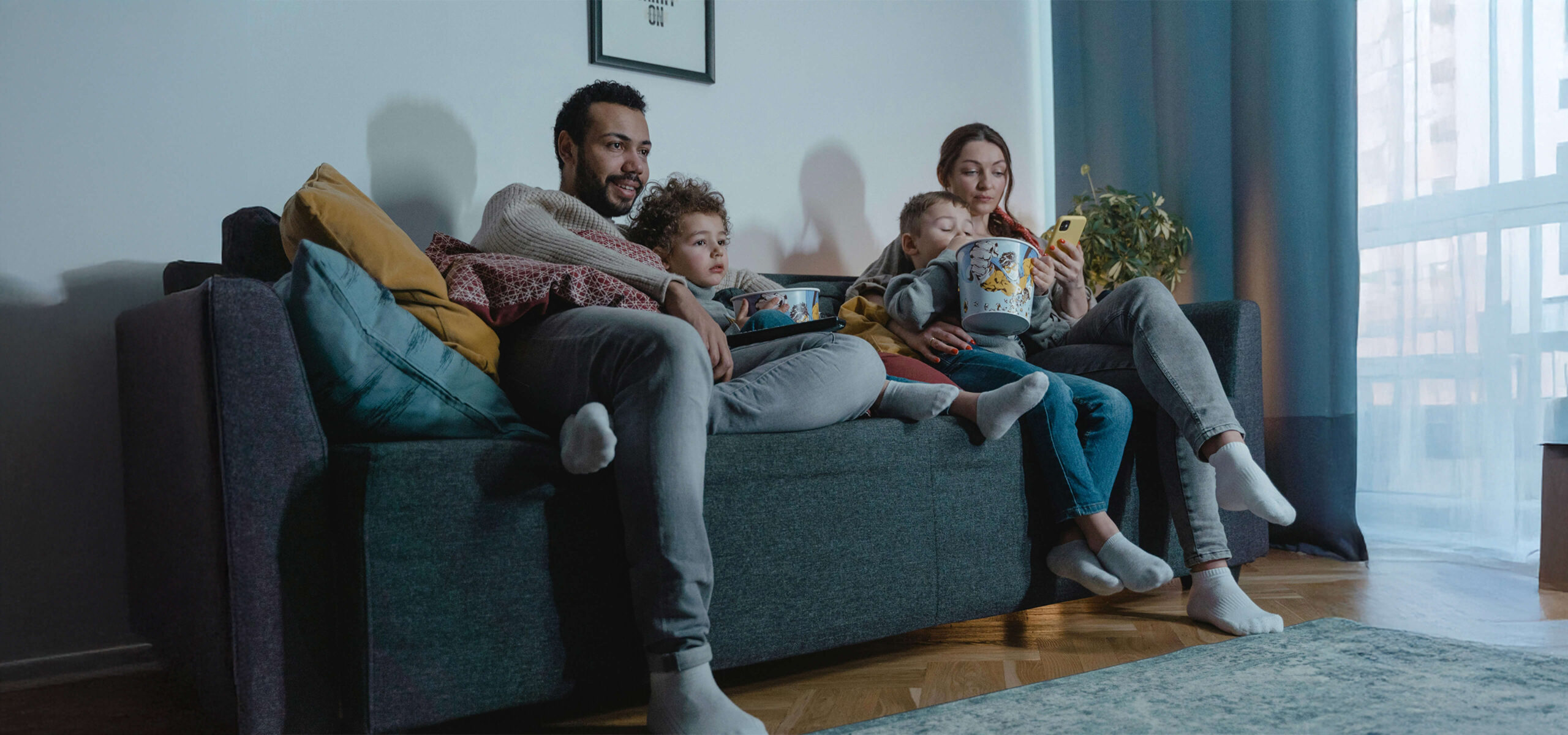 family sitting on a sofa eating popcorn scaled